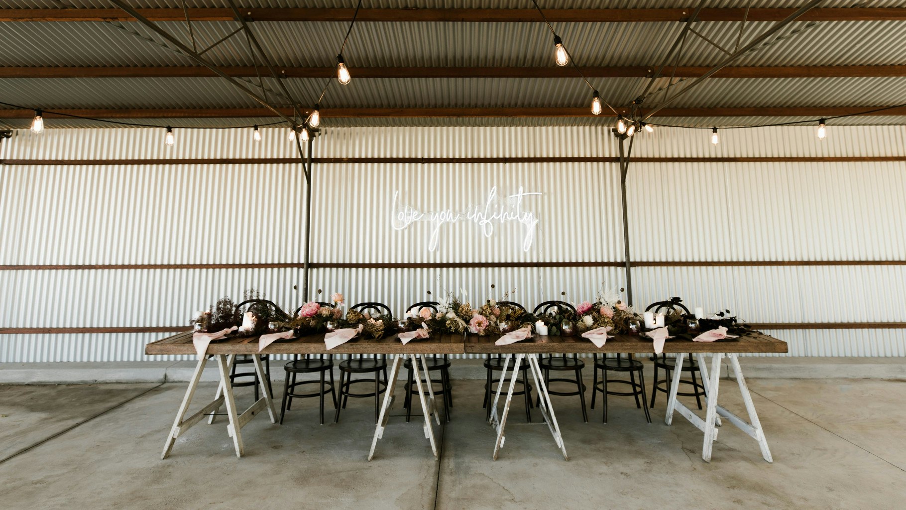 Tin shed with wedding party table setup with florals and lighting.